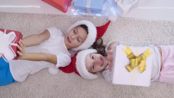 Tevreden kinderen pronken met hun cadeautjes, kijken naar de camera, glimlachen. — Stockvideo