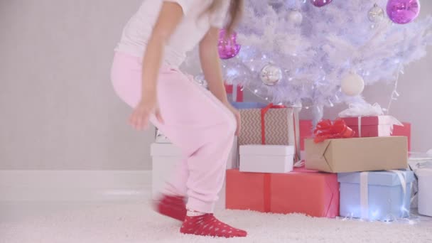 一个好奇的小女孩晚上不声不响地来到圣诞树前，打开礼品盒，从里面发出神奇的光，孩子们看到没人看见她，就关上礼品盒，把它放了回去. — 图库视频影像