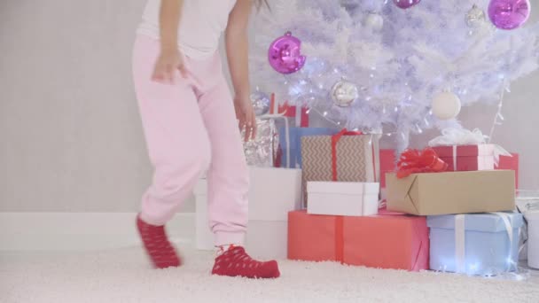 La niña curiosa llega desapercibida al árbol de Navidad por la noche, abre una caja de regalo, la luz mágica ilumina desde el interior, el niño comprueba que nadie la ve, cierra la caja y la roba . — Vídeo de stock