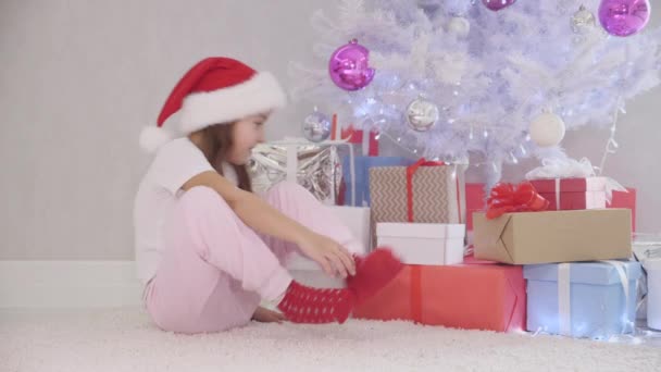 Interesting video of pretty kid slealing a gift box fom under the christmas tree at night. — Stock Video