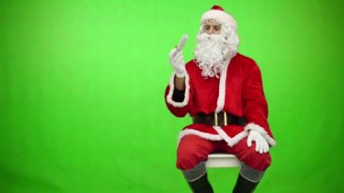 Noel Baba krom anahtar yeşil ekranı okuyor. Noel Baba yeşil üzerine izole edilmiş göğsünden bir kağıt parçası çıkarır.