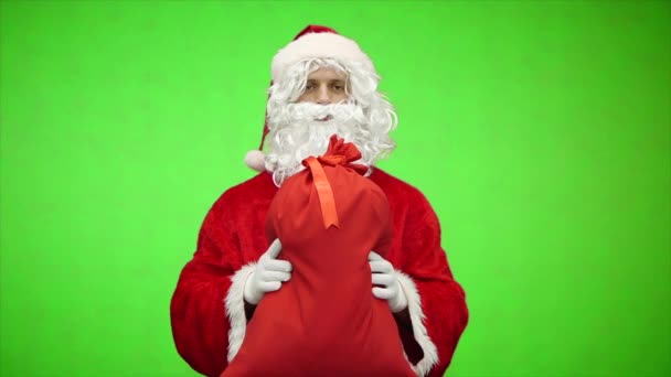 Portret van de Kerstman geven tas met geschenken op groene achtergrond. Langzame beweging. — Stockvideo