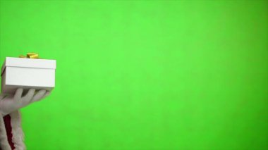 Noel Baba yeşil bir arka planda hediye kutusu tutuyor.