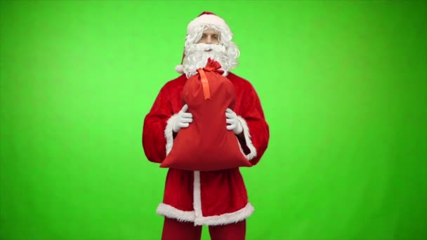Jultomten ger väska med gåvor på grön bakgrund. Långsamma rörelser — Stockvideo