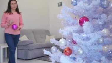 Güzel genç bayan Noel ağacı süslemekten memnun, tatil ruhunun keyfini çıkarıyor..