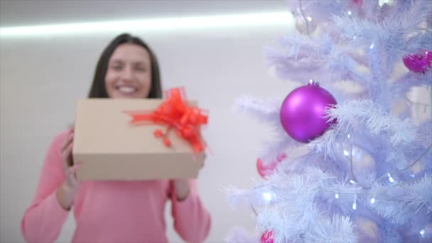 Moment flou de la façon dont maman heureuse, a trouvé un cadeau pour elle-même sous l'arbre de Noël et l'étend à la caméra, se sentant reconnaissante . — Video