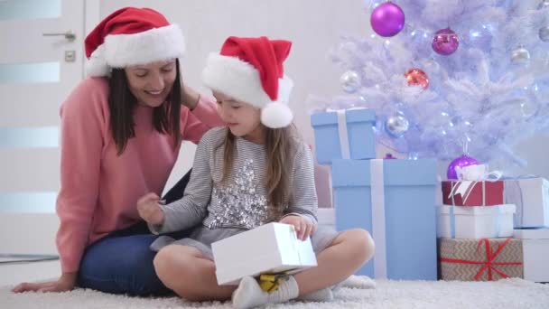 Sedikit cutie membuka bungkusan hadiah, ibunya memberinya pada pagi Natal . — Stok Video