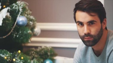 Sakallı adamın Noel ağacına bakıp kameraya başparmağını uzattığı yakın çekim videosu..