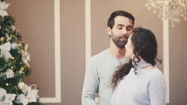 Pareja romántica bailando y apreciando el tiempo juntos en casa con árbol de Navidad sobre fondo gris . — Vídeos de Stock