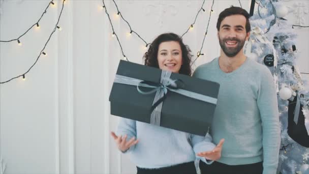 Powolny film z wesołą nieostrożną parą z uśmiechem na twarzy, śliczna dziewczyna rzuca i łapie pudełko noworoczne. — Wideo stockowe
