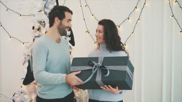 Ragazzo affettuoso che dà regalo alla sua ragazza mentre festeggia il nuovo anno . — Video Stock