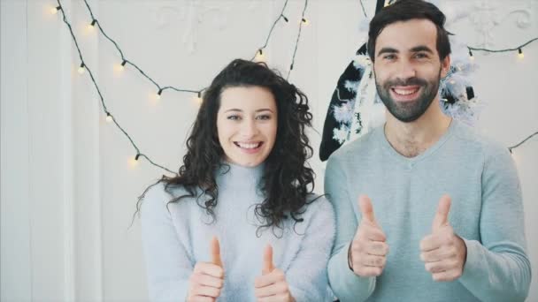 Ano Novo vídeo de casal infantil perto da árvore de Natal, dando polegares para cima e sorrindo . — Vídeo de Stock