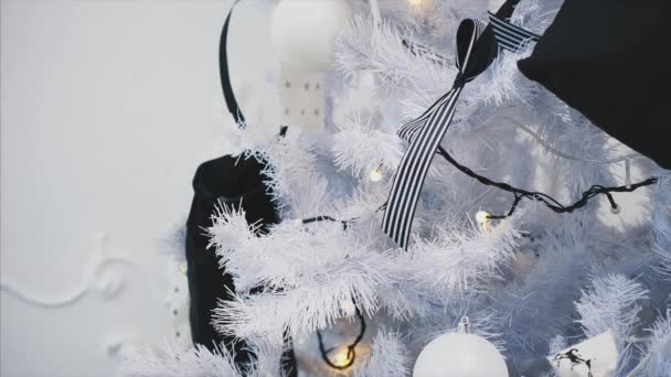 一个孩子的手把带条纹的弓放在圣诞树树枝上. — 图库视频影像