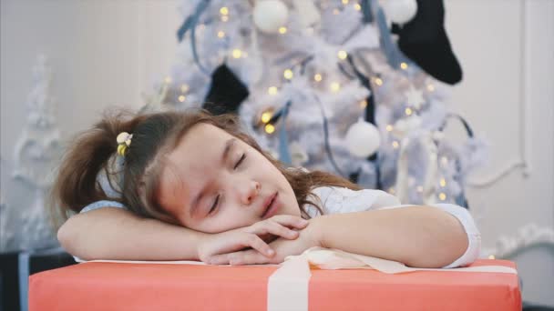 Närbild 4k vidoe av söt flicka sover på stora julklapp, ser fantastisk. — Stockvideo