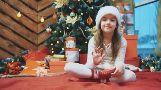 4k video perempuan muda mengenakan topi natal tangan melambaikan tangan, mengundang semua orang untuk merayakannya dengan dia di latar belakang kayu . — Stok Video