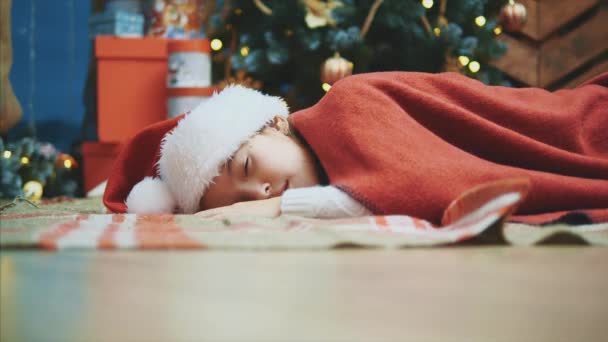 Eine Hand des Weihnachtsmannes legt eine Geschenkbox in die Nähe eines Mädchens, während es schläft. — Stockvideo