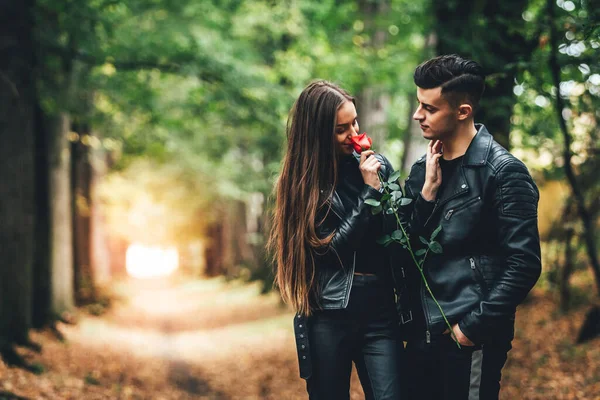 Szép elegáns férfi és nő társkereső őszi parkban, ő szaga egy rózsa, hogy ő ad neki. — Stock Fotó
