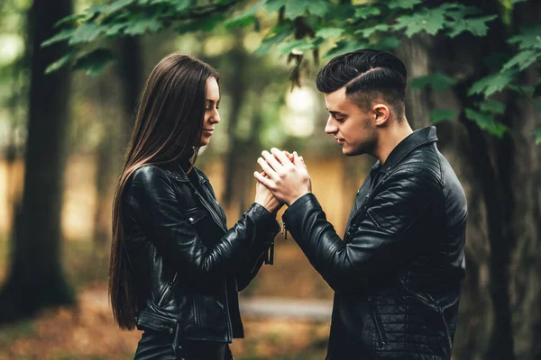 Casal jovem no parque natural florestal no final do outono. O homem aquece as mãos das meninas . — Fotografia de Stock