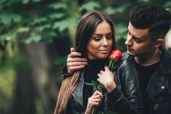 Šťastná dívka s červenou růží říká díky svému příteli během jejich procházky v parku. — Stock fotografie