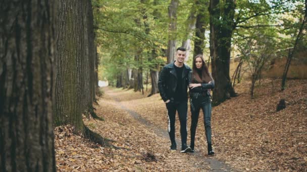 Een liefdevol koppel wandelt in het najaarspark. Wazig begin. Een sterke man knuffelt is een vriendin. Langzame beweging. Begrepen, ruimte. 4K. — Stockvideo