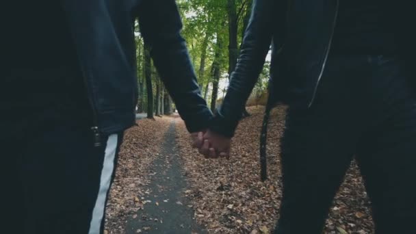 Pareja irreconocible pasea en el parque de otoño. Mirada negra total. Fondo borroso. Lento. Cultivo. Copiar espacio. 4K . — Vídeo de stock