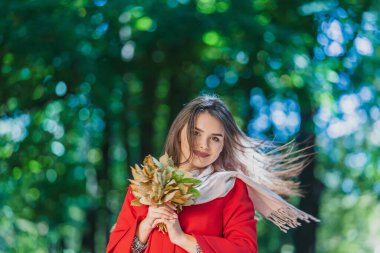 Hayatı daha iyi yapan küçük şeylerdir. Turuncu yapraklı tatlı kız, şehir parkında eğleniyor..