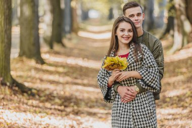 Genç aile sarı ağaçların ve yaprakların arasında eğleniyor..
