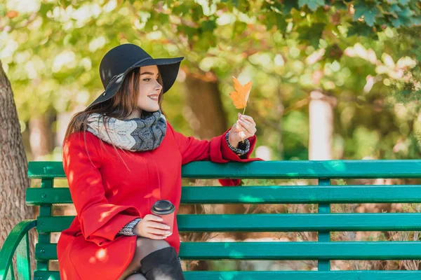 Wanita jatuh minum kopi di taman kota musim gugur, menikmati daun kuning yang indah dan kedamaian musim gugur. — Stok Foto