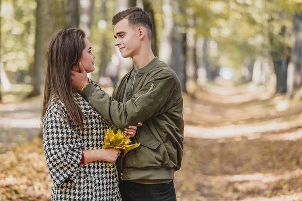 Ρομαντικό ζευγάρι χαλαρώνοντας στο πάρκο φθινόπωρο, αγκαλιά, απολαμβάνοντας καθαρό αέρα και όμορφο καιρό φθινόπωρο. — Φωτογραφία Αρχείου