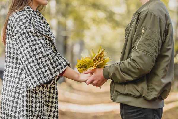 Осіння концепція. Букет з яскравого барвистого осіннього листя в руках двох закоханих людей на тлі розмитого парку . — стокове фото