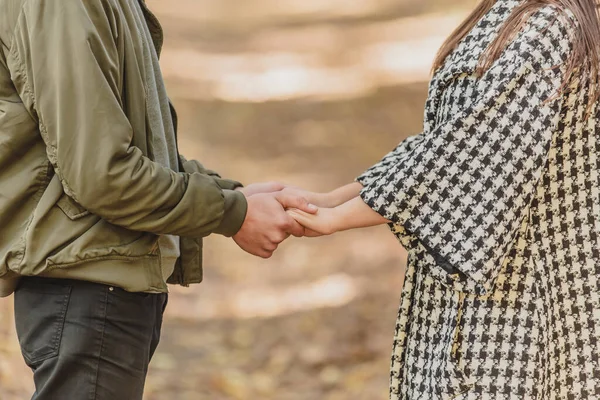 Обрізана фотографія закоханої пари, що тримає руки в осінній природі з сонячними променями всюди . — стокове фото
