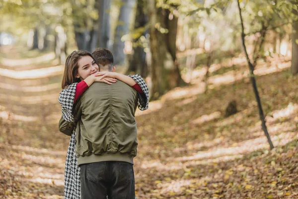 Eufórikus fiatal pár találkozó és ölelés őszi parkban hosszú idő után a távolban. — Stock Fotó