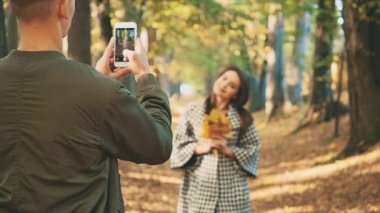 Yavaş ol. Güz Ormanı Parkı 'nda sevgili bir çift fotoğraf çekiyor. Uzayı kopyala Arka plan bulanık. 4K