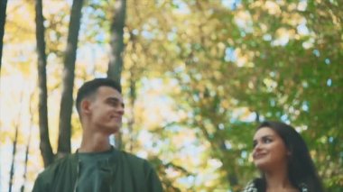 Yavaş ol. Sevgi dolu bir çift sonbahar parkında yürüyor. Gülümsüyorlar ve konuşuyorlar. Bulanık alçak görüntü. Uzayı kopyala 4K.