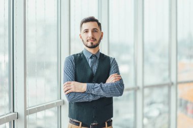 Kendine güvenen genç işadamı elleri bağlı, kameraya bakıyor, sıkı çalışmaya hazır..