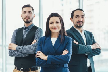 Profesyonel bir iş ekibinin grup fotoğrafı. Elleri bağlı kameraya güvenle bakıyorlar..