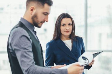 Takım elbiseli iki çalışanın ellerinde kağıtlarla patronlarının önünde konuşma hazırlarken gergin olduklarını görmek..