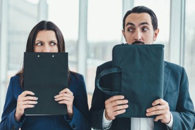 Yüzünü panonun arkasına saklayan kadın, yüzünü dizüstü bilgisayarın arkasına saklayan adam..