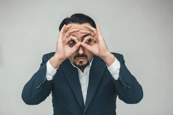 Extraño comportamiento del hombre de negocios manteniendo las manos como binoculares y mirando sospechosamente a algo . —  Fotos de Stock
