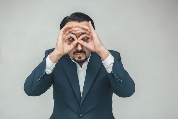 Extraño comportamiento del hombre de negocios manteniendo las manos como binoculares y mirando sospechosamente a algo . —  Fotos de Stock