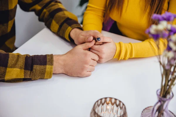 Egy szerelmes pár fogja egymás kezét a fehér asztalon. Vágott fénykép felülről, felülnézet másolási hellyel. — Stock Fotó