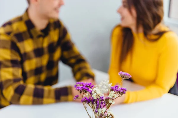 Tiro recortado de casal romântico tendo jantar romântico em evento especial. Concentre-se em flores violetas na vanguarda . — Fotografia de Stock