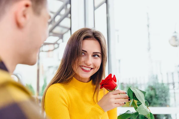 Хлопець зустрічається з коханою, дарує їй велику червону троянду, він знає, що жінки люблять квіти. Фокус на дамі, що блищить із задоволенням, тримає квітку . — стокове фото