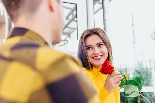 Namorado tem encontro com a namorada, dá-lhe uma grande rosa vermelha, ele sabe que as mulheres gostam de flores. Foco está na senhora irradiando com prazer, segurando uma flor . — Fotografia de Stock