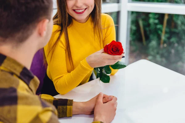 Vystřižený záběr mladých lidí, setkání v kavárně při zvláštní příležitosti, chlapec dal červenou růži své roztomilé přítelkyni. — Stock fotografie