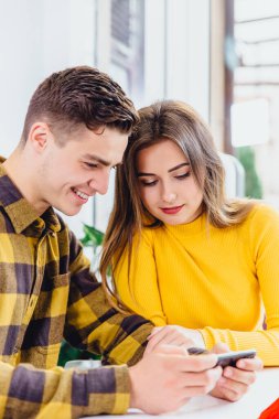 Akıllı telefondan oyun oynayan komik bir çift, kafeteryada yemek yerken...