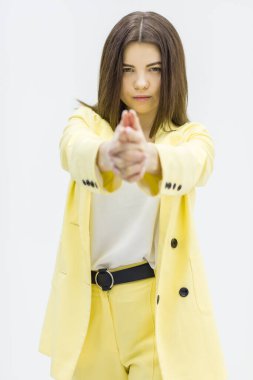 Beyaz arka planda duran genç bir kadın ateş ediyor..