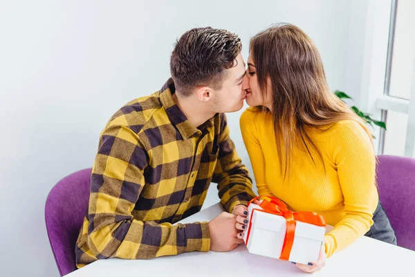 Concetto di San Valentino. Giovane uomo e donna si stanno baciando, ragazza tiene un regalo dal suo fidanzato. — Foto Stock