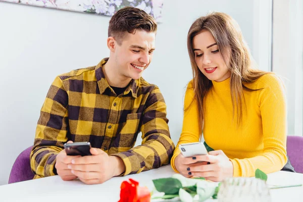 Hermosa pareja joven está utilizando teléfonos inteligentes para mirar a través de contenido de redes sociales y compartir cosas interesantes con su pareja . — Foto de Stock