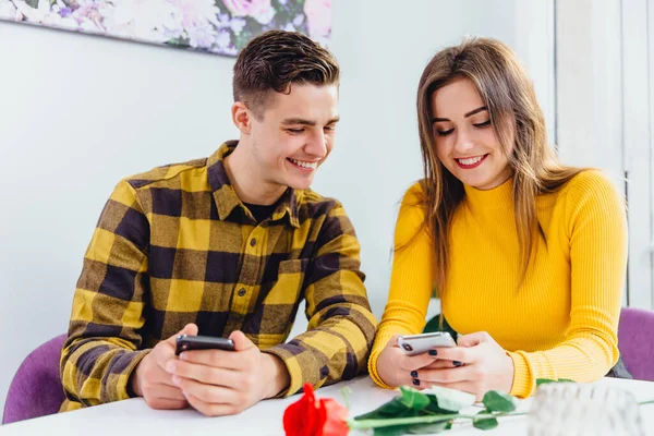 Hermosa pareja joven está utilizando teléfonos inteligentes para mirar a través de contenido de redes sociales y compartir cosas interesantes con su pareja . — Foto de Stock